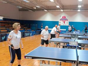 a group of people standing around a ping pong table at Hostel Rakietka in Gdańsk