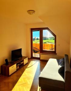 een woonkamer met een bank, een tv en een raam bij Residence Aurora, Bohinj in Bohinj