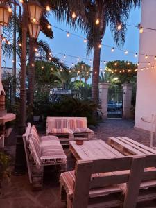 a patio with benches and lights and palm trees at acquaesale rooms in Porto Cesareo
