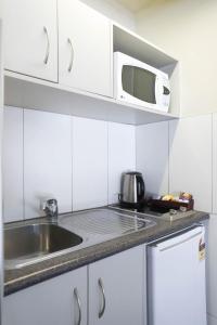 cocina blanca con fregadero y microondas en Airport Manor Inn en Auckland