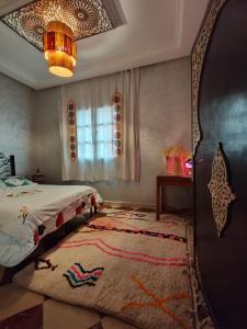 una camera con letto, tappeto e lampadario pendente di DAR SARSAR airport a Marrakech