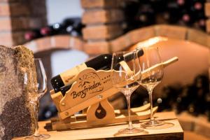 tre bicchieri da vino seduti su un tavolo con bottiglie di vino di Hotel Bergfrieden a Martello