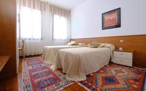 two beds in a room with a rug at Le Luise in Valdobbiadene
