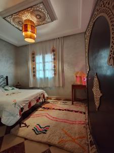 una camera con letto, tappeto e lampadario pendente di DAR SARSAR airport a Marrakech