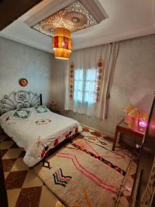 a bedroom with a bed and a rug and a chandelier at DAR SARSAR airport in Marrakesh