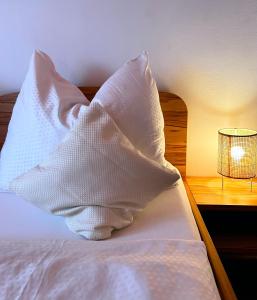 uma almofada branca sentada numa cama ao lado de um candeeiro em Frühstückspension Elena Nicoleta Caltun em Fischamend Dorf