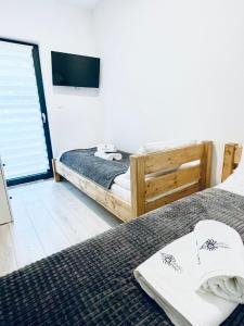 a bedroom with two beds and a tv on the wall at Szczyrkowskie SKI & FUN 3 z balkonem - Sauna i Jacuzzi in Szczyrk