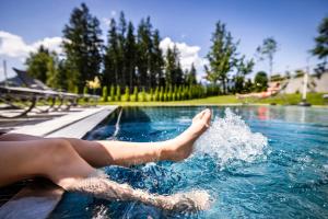 a person laying on the edge of a swimming pool at Der Alpenblick in Sankt Johann im Pongau