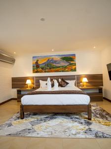 een slaapkamer met een groot bed en een schilderij aan de muur bij LIGHT VILLAS in Nairobi