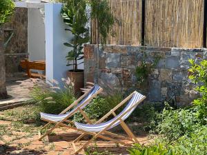 two lawn chairs sitting in a yard next to a stone wall at Gioma Garden Villas in Istro