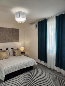 a bedroom with a bed with blue curtains and a chandelier at Dolce vita Prémium in Budapest