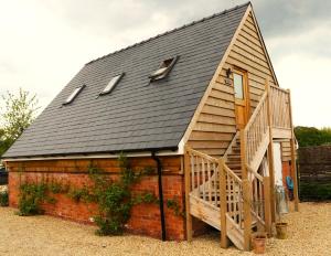 uma pequena casa com um telhado de gambrel e uma escada em The Loft at the Croft - Stunning rural retreat perfect for couples & dogs em Leigh