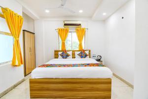 um quarto com uma cama grande e cortinas amarelas em FabHotel Grand Hazra Inn - Nr Ballygunge Station em Calcutá