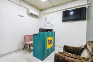 FabHotel Grand Hazra Inn في كولْكاتا: غرفة بها كرسيين وتلفزيون على الحائط