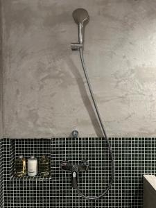松山市にあるグループに最適The Bath & Bed Dogo 築110年の蔵をリノベした源泉掛け流し一棟貸しの温泉宿のバスルーム(タイル張りの壁にシャワーヘッド付)