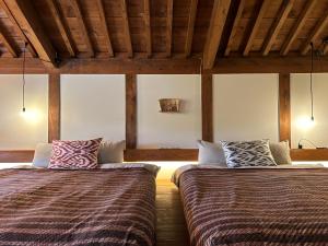 松山的住宿－The Bath & Bed Dogo 築110年の蔵をリノベーションした源泉掛け流しのお宿，配有木天花板的客房设有两张床。