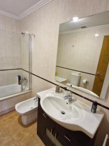 a bathroom with a sink and a mirror and a toilet at Apartamento playa Carrabuxeira (Sanxenxo) in Sanxenxo +22 photos