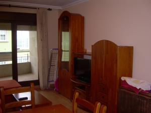 a living room with a tv and a wooden cabinet at Apartamento playa Carrabuxeira (Sanxenxo) in Sanxenxo
