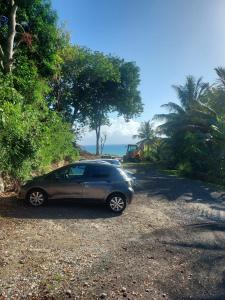 un coche aparcado al lado de una carretera cerca del océano en Location Dampierre en Le Gosier