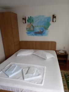 een bed met witte lakens en een schilderij aan de muur bij Casa Tulceanu in Sulina