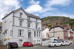 a white house with cars parked in front of it at Abbey Road Boutique Holiday Apartment in Llandudno