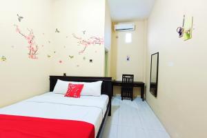 a bedroom with two beds and a red blanket at OYO 93837 Ipeda Family Residence in Banyuwangi