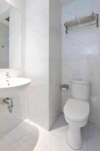 a white bathroom with a toilet and a sink at OYO 93837 Ipeda Family Residence in Banyuwangi