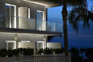 a house with a glass facade with a palm tree at Terrazze Naos in San Leone