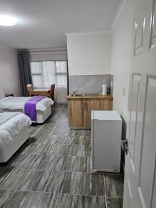 a bedroom with two beds and a bathroom with a sink at HAGAR LODGE in Mid Illovo
