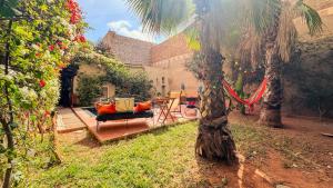 ein Haus mit einer Veranda mit einer Hängematte und einer Palme in der Unterkunft Janna d'Ifni in Sidi Ifni