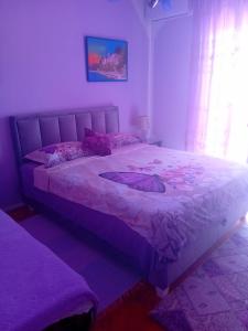 - une chambre avec un grand lit et une couette violette dans l'établissement Guest House Cinderella, à Herceg-Novi
