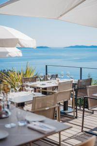 a restaurant with tables and chairs with a view of the ocean at Hôtel La Villa Douce in Rayol-Canadel-sur-Mer