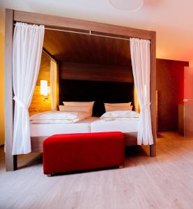 a bedroom with two beds and a red bench at Ringhotel Forellenhof in Walsrode