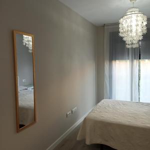 um quarto com um espelho e um lustre em Apartamento MyR em Benajarafe