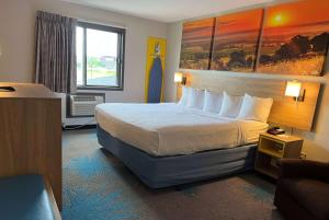 Days Inn & Suites by Wyndham Des Moines Airport في دي موين: غرفة فندقية بسرير كبير ونافذة
