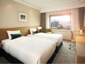 ソウルにあるノボテル アンバサダー ソウル江南のベッド2台と窓が備わるホテルルームです。
