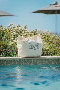 a white bag sitting next to a swimming pool at Hôtel La Villa Douce in Rayol-Canadel-sur-Mer