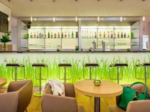 a restaurant with a green wall with tables and chairs at ibis Hotel Hannover Medical Park in Hannover