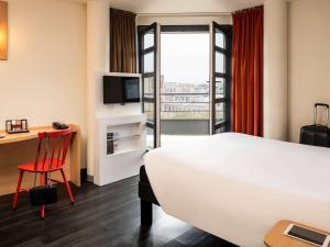 パリにあるイビス パリ ガール ドゥ リヨン ディドゥロのベッド、デスク、テレビが備わるホテルルームです。