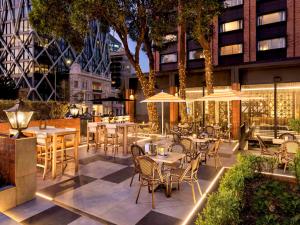 um restaurante ao ar livre com mesas, cadeiras e guarda-sóis em Pullman Auckland Hotel & Apartments em Auckland