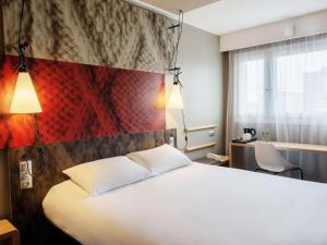 Pokój hotelowy z białym łóżkiem i czerwoną ścianą w obiekcie ibis Warszawa Centrum w Warszawie