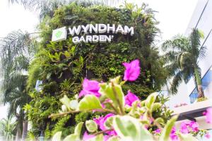 un panneau indiquant le jardin de wynatown avec des fleurs roses dans l'établissement Wyndham Garden Guayaquil, à Guayaquil