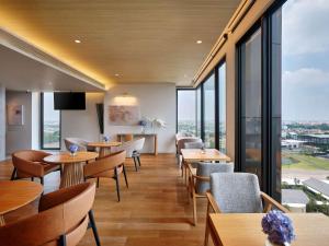 un restaurante con mesas, sillas y ventanas grandes en Novotel Bangkok Future Park Rangsit, en Pathum Thani