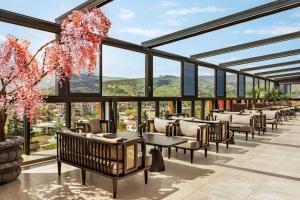 a restaurant with tables and chairs and large windows at Ramada by Wyndham Tbilisi Old City in Tbilisi City