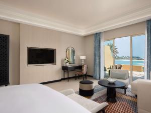 ラス・アル・ハイマにあるSofitel Al Hamra Beach Resortのベッドとリビングルームが備わるホテルルームです。