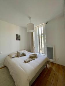 ein weißes Schlafzimmer mit einem großen Bett und einem Fenster in der Unterkunft Montfaucon - Élégant appartement & terrasse au cœur de Bordeaux, idéalement situé in Bordeaux