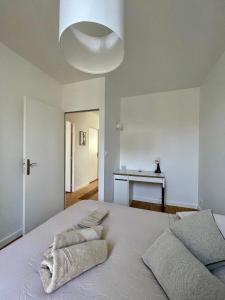 ein weißes Schlafzimmer mit einem Bett mit zwei Handtüchern darauf in der Unterkunft Montfaucon - Élégant appartement & terrasse au cœur de Bordeaux, idéalement situé in Bordeaux