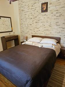 a large bed in a bedroom with a brick wall at Cozy Rooms in Vratsa by Georgievi in Vratsa