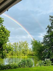 ein Regenbogen am Himmel über einem See in der Unterkunft Maison avec accès au lac in Izon