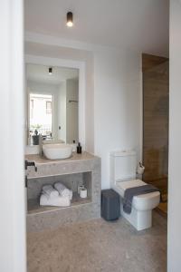 a bathroom with a sink and a toilet and a mirror at Griffin Suites in Heraklio
